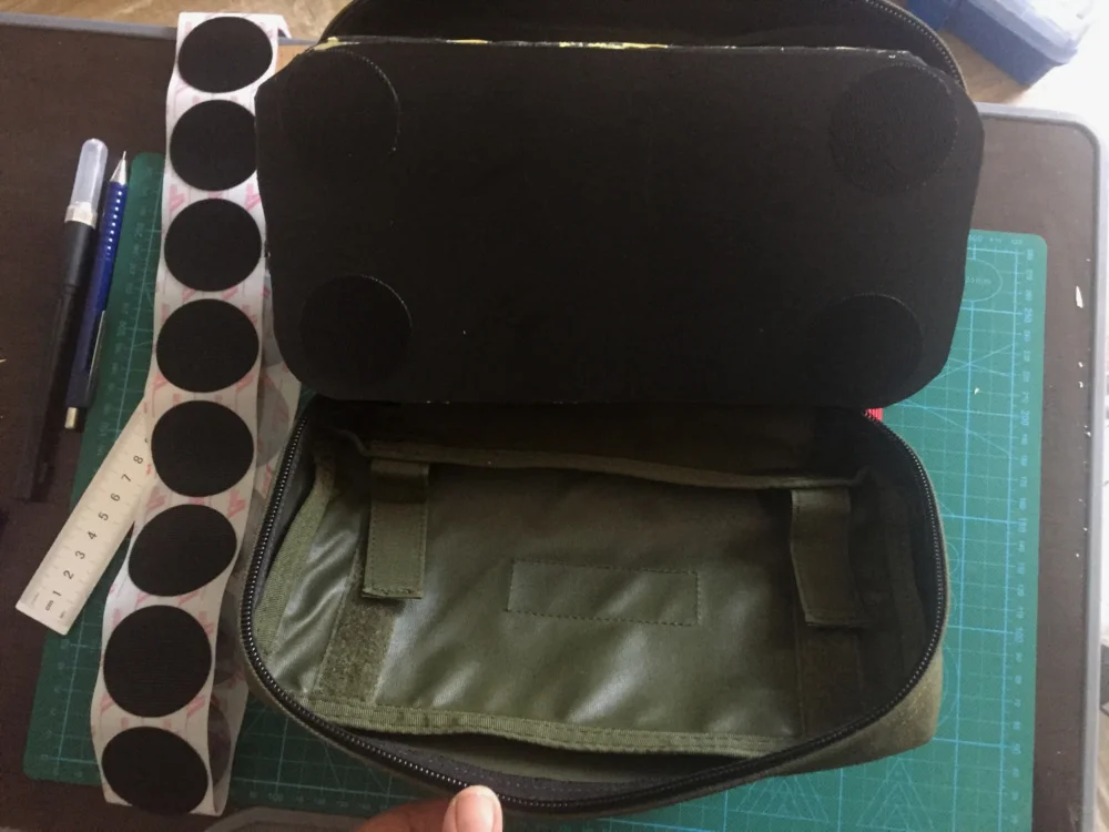 Step 2: 这个医疗包内部还有魔术贴毛面，应该是用来固定别的东西的。正好手头有头盔里用的带背胶的魔术贴钩面圆片，刚好可以派上用场。EVA海绵块最底部衬了一块塑料片，从旧文件夹上剪下来的