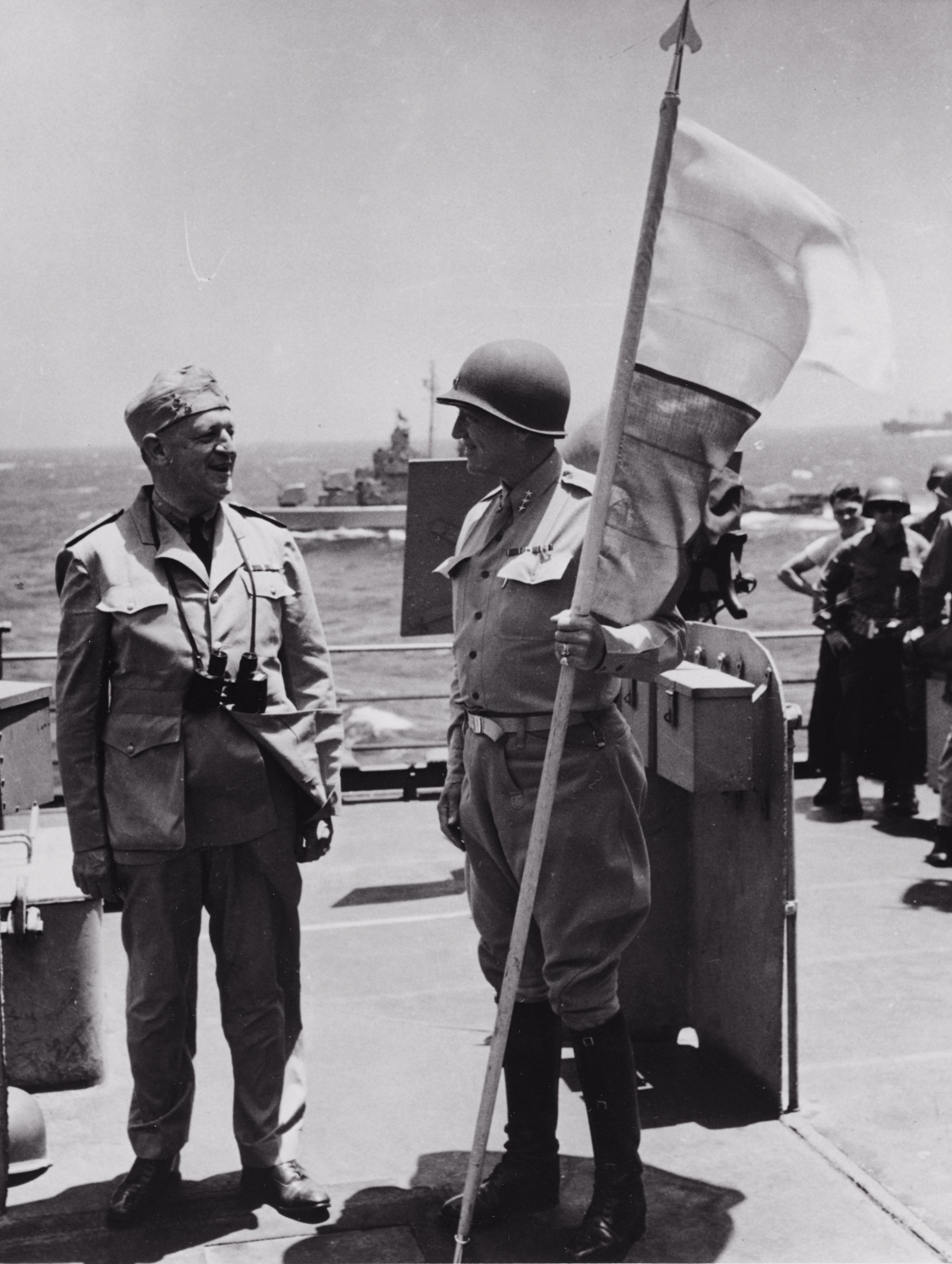 手持第七集團軍軍旗的巴頓將軍，攝於蒙羅維亞號上。