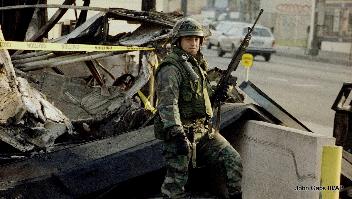 A California National Guardsman stands guard over ruins of a shop in Koreatown in Los Angeles, Saturday, May 2, 1992.