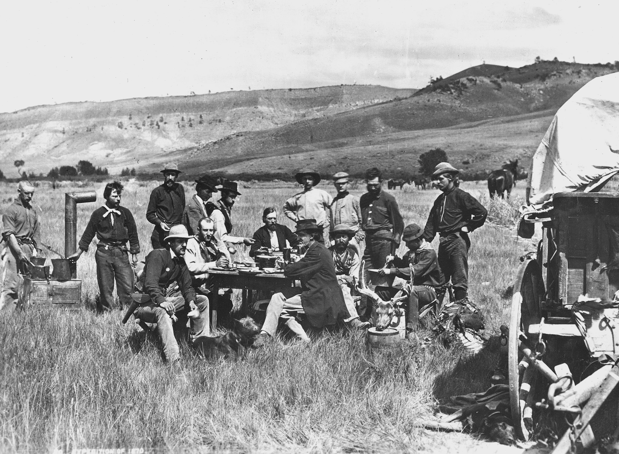 费迪南德海登营地的午餐，1870年8月24日拍摄于怀俄明州。海登穿着深色夹克坐在桌子的一端。