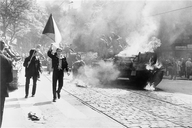 圖注：1968 年 8 月，布拉格市民在燃燒的蘇軍坦克旁揮舞國旗。