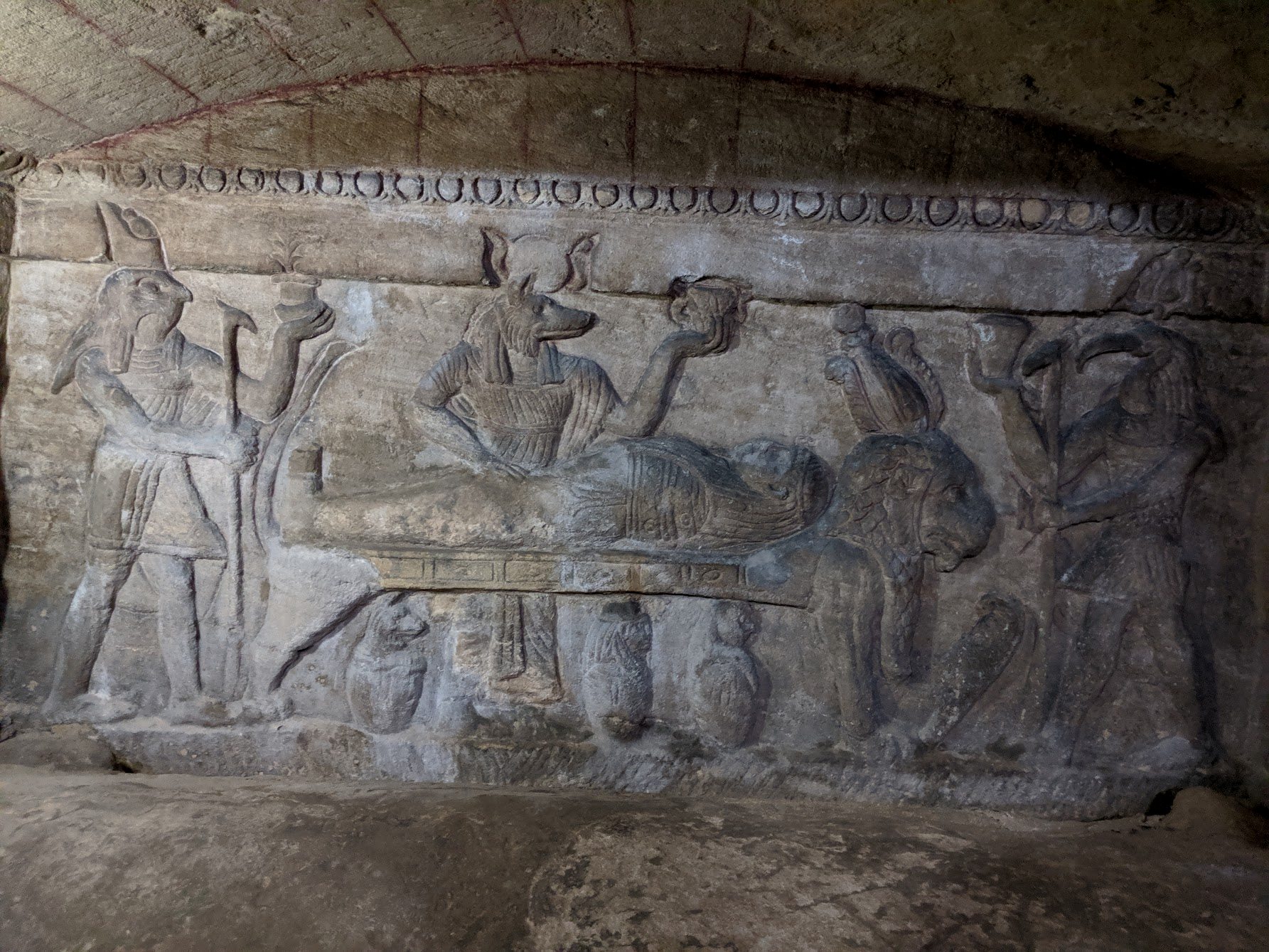 门后的古埃及风格浮雕，从左至右为天神荷鲁斯、死神阿努比斯、书写之神托特（负责评定死者的善恶）；木乃伊所躺的狮子床则戴着冥神奥西里斯的帽子