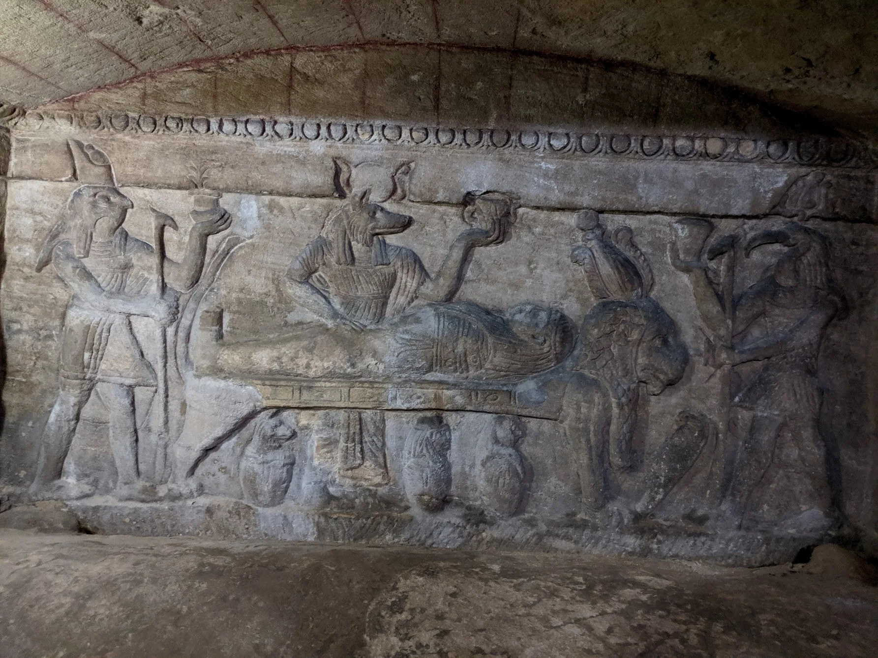 门后的古埃及风格浮雕，从左至右为天神荷鲁斯、死神阿努比斯、书写之神托特（负责评定死者的善恶）；木乃伊所躺的狮子床则戴着冥神奥西里斯的帽子