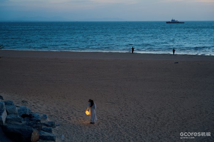 蓝调时刻的海滩，游客点亮了一只灯笼