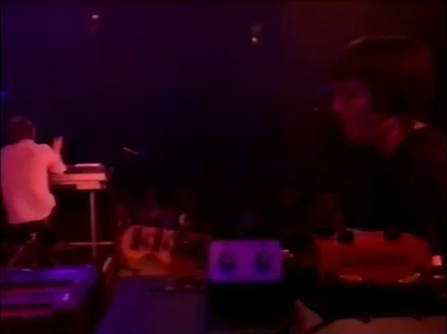 一张截图：Colin 的效果器被放在机架盒顶部。截图来自 Radiohead 于2003年六月5日的 MTV $2 Bill 表演的 Everything In Its Right Place 现场。