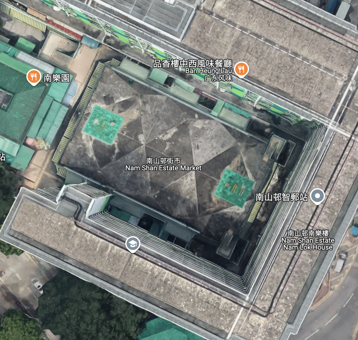 顺着街市楼梯走上平台顶层，你会发现一个略显隐蔽的活动空间。从俯瞰图来看，这个空间的几何图案与南山邨的住宅楼完美融合，给人一种有趣的视觉效果，像是两个伞公司的Logo重合。南山邨的建筑群环绕着这个开放的中心区域，形成了一个集住宅、商业和公共设施为一体的紧密社区。