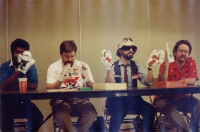 88年GenCon展子上的设计师们摆弄Bullwinkle & Rocky的玩具。从左到右依次是Mike Pondsmith（没错，赛博朋克高手！译者：这位就是2077原著作者），Lawrence Schick, 我, 和 Zeb Cook