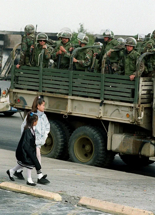 Two girls walk by a truck of National Guardsmen in Los Angeles in 1992. (AP)