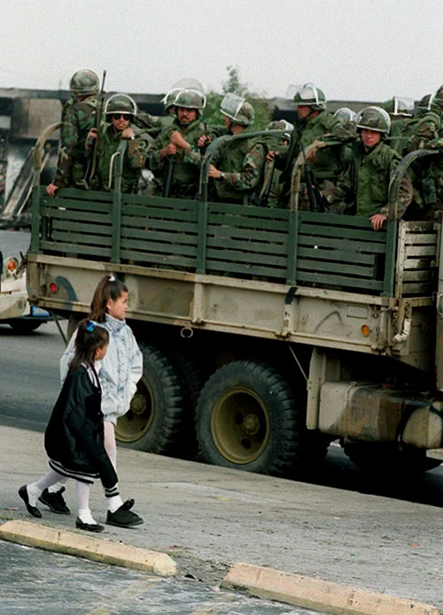 Two girls walk by a truck of National Guardsmen in Los Angeles in 1992. (AP)