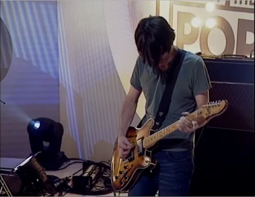 一张截图：Jonny 站在 Petersen Special 前，摄于 Radiohead 在2001年5月17日的 Top of The Pops 表演 Knives Out 时。