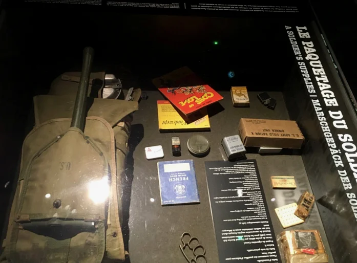 D日登陆时美军的单兵装备。左边是M-1928作战背包和M-1943折叠铲。蓝色的小册子是配发的法语教材。士兵甚至带了指虎，也是做好了肉搏的觉悟